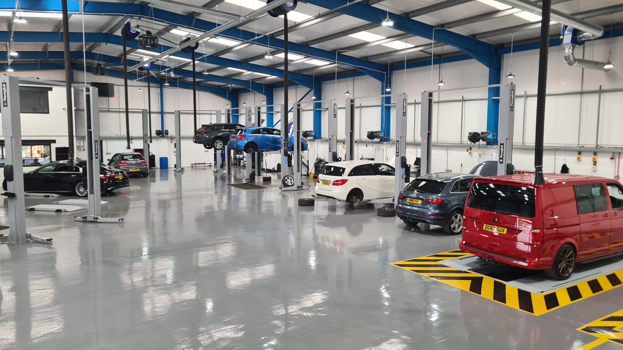 The workshop with several vehicle lifts and cars under bright lights