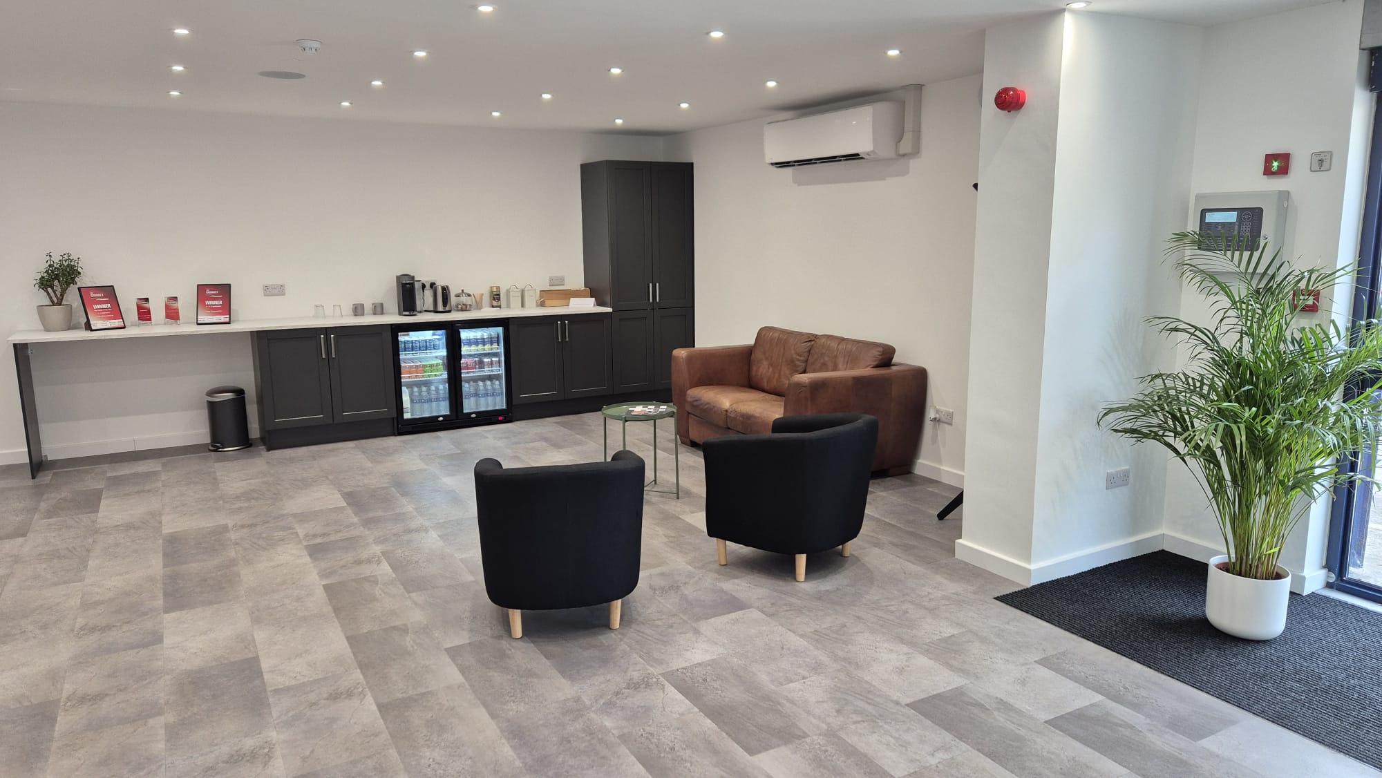 The customer waiting area with leather armchairs, a drinks fridge and a palm