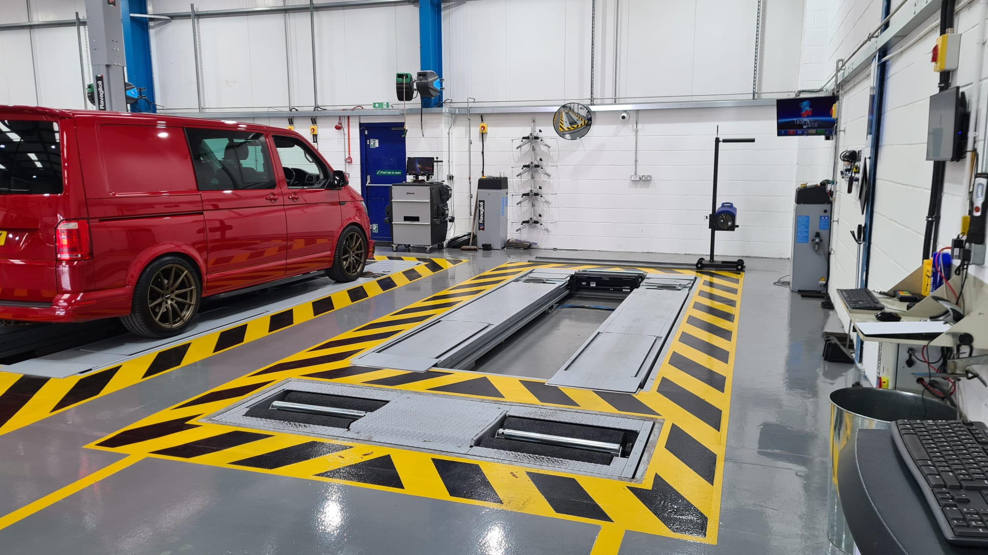 A service bay with an inspection pit and a red VW van